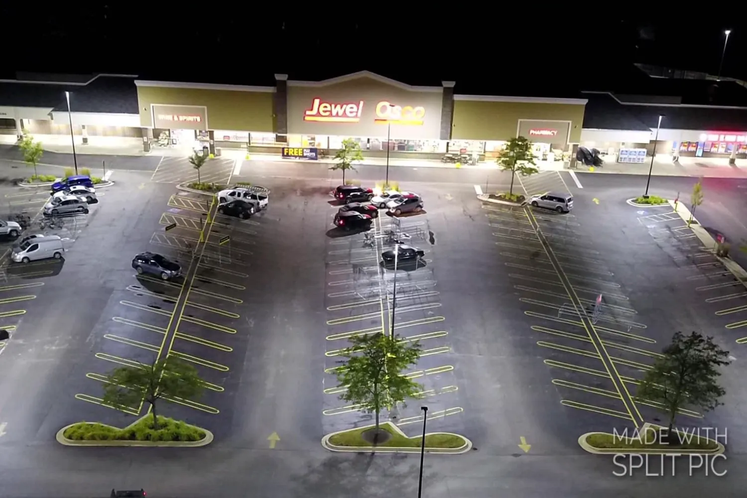 Aerial view of a nearly empty Jewel-Osco parking lot at night, with a few parked cars and illuminated store signage
